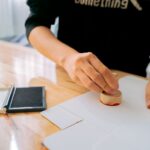 Person stämplar vita dokument bredvid ett öppet stämpeldynsfodral